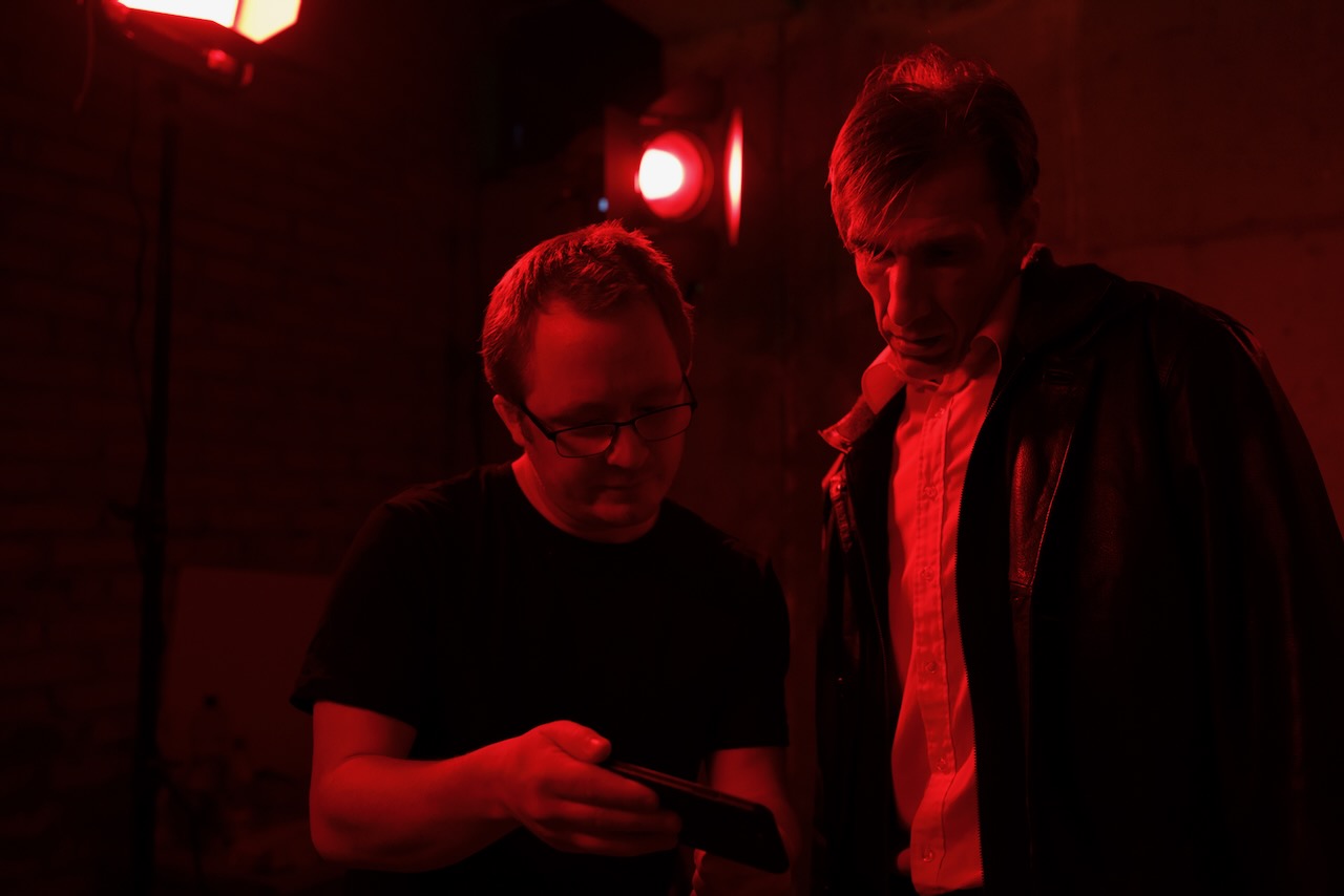 The director showing a phone to an actor.