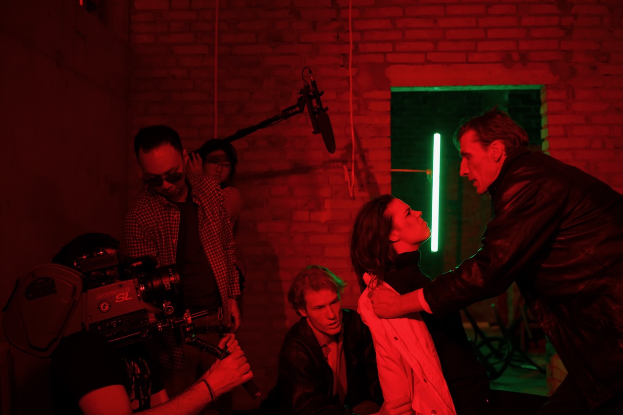 Camera and boom recording a scene against a brick wall.