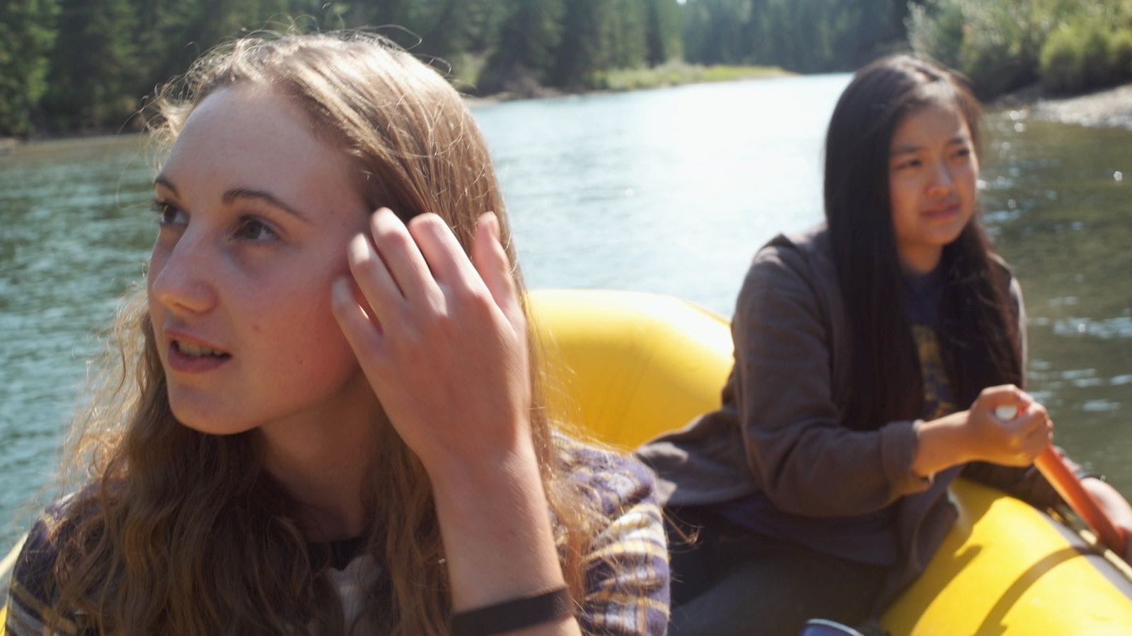 Two young women in a yellow raft on a river.
