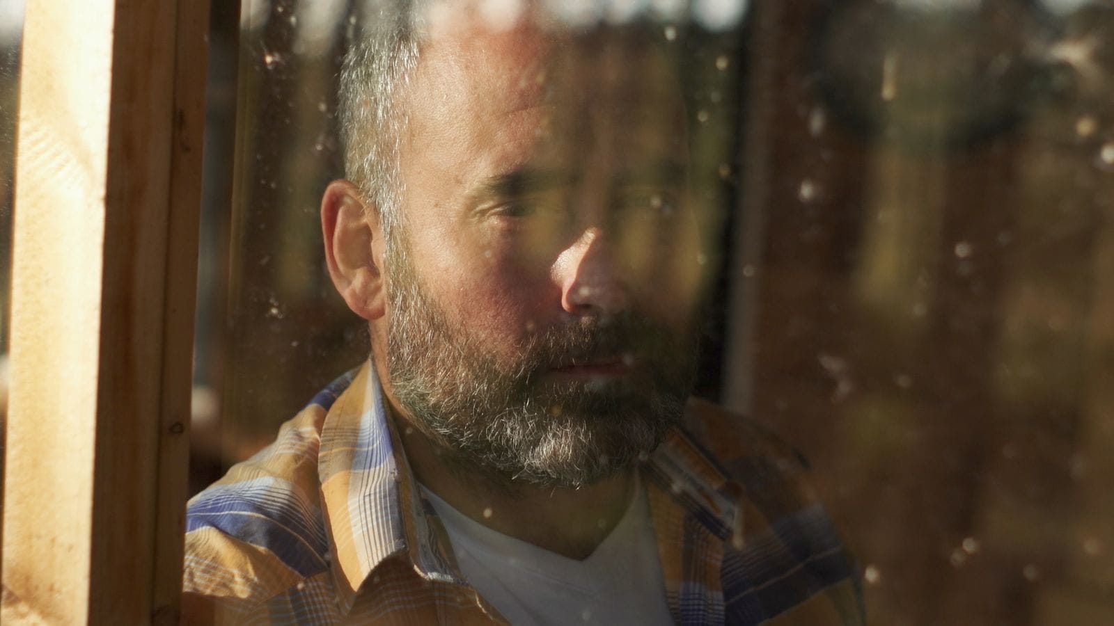 A man looking through a dusty window.